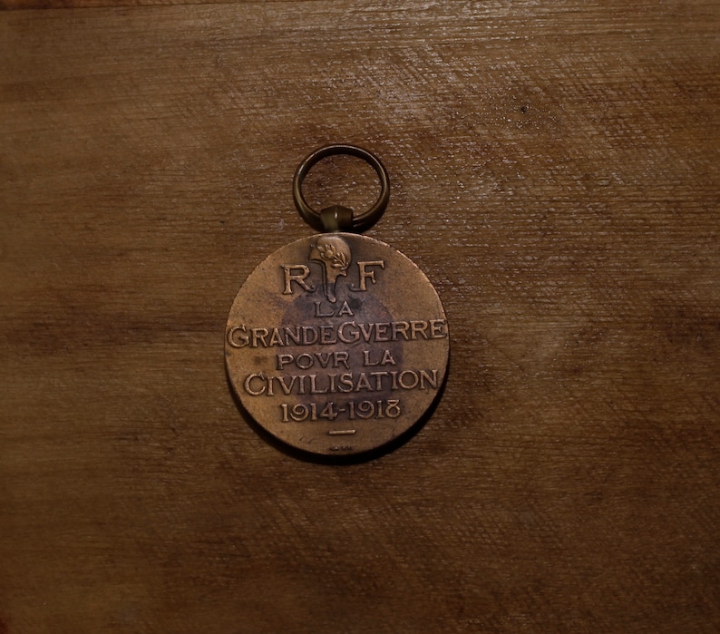 May include: A bronze medal with a loop for hanging. The front of the medal has the text "R.F. LA GRANDE GUERRE POUR LA CIVILISATION 1914-1918".