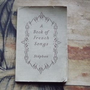 May include: A vintage book titled "A Book of French Songs" by St&eacute;phan. The cover features a decorative border with a floral design.