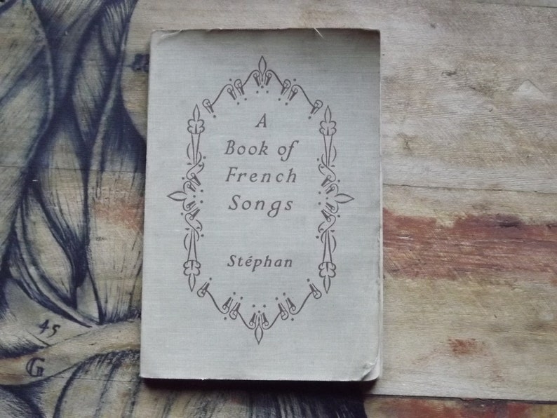 May include: A vintage book titled "A Book of French Songs" by St&eacute;phan. The cover features a decorative border with a floral design.