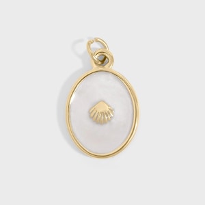 May include: Gold-tone oval pendant with a white enamel center and a gold seashell design. The pendant has a loop at the top for attaching to a chain or bracelet. The seashell is centered on the white background.