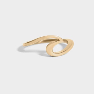 May include: A gold wave ring. The ring is made of a smooth, polished metal and is shaped like a wave.