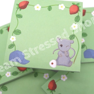 May include: A set of green sticky notes with a cute mouse wearing a baseball cap and strawberries and flowers on a vine. The notes are perfect for taking notes, leaving reminders, or adding a touch of whimsy to your desk.