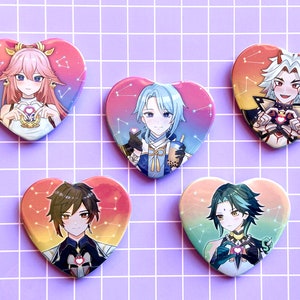 Peut inclure: Ensemble de cinq badges en forme de cœur avec des illustrations de personnages de style anime. Chaque badge présente un personnage différent avec un code couleur unique et un fond de constellation. Les couleurs incluent le rose, l'orange, le bleu et le vert.