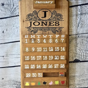 May include: A wooden calendar with a floral design and the name "JONES" in black lettering. The calendar is for January and has a small wooden block with the text "4th of July" on it.
