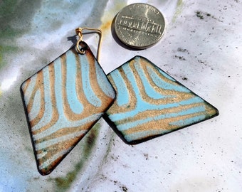 May include: A pair of geometric earrings with a blue and gold pattern. The earrings are made of metal and have a diamond shape.