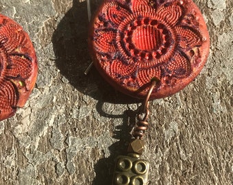 Highly textured red polymer clay earrings with vintage button pattern.