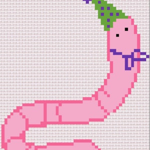 May include: A pink worm wearing a green and purple party hat with purple polka dots. The worm has a purple bow tie and a happy face.
