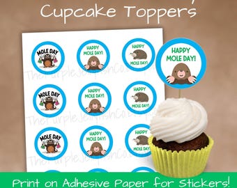 Pode incluir: Toppers de cupcake imprimíveis do Dia da Toupeira com seis designs diferentes. Os toppers apresentam um desenho animado de toupeira com o texto "Mole Day" e "Happy Mole Day!" em um círculo azul. Um cupcake com cobertura branca também é visível.