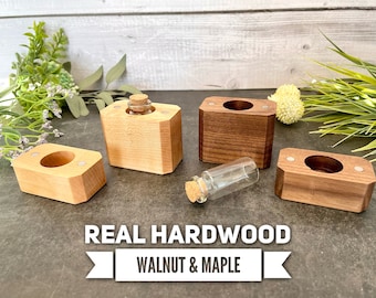 May include: Four small wooden boxes with lids, two made of maple and two made of walnut. The boxes are arranged in a square shape with a small glass bottle in the center. The boxes are labeled "REAL HARDWOOD WALNUT & MAPLE".