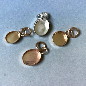 Peut inclure: Quatre supports de pendentifs ovales en or, argent et cuivre. Chaque support est doté d'une petite boucle pour l'attacher à une chaîne ou à un autre composant de bijouterie. Les pendentifs sont vides, prêts à être embellis.