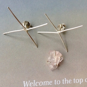 Peut inclure: Deux montures de boucles d'oreilles argentées à quatre griffes chacune, et une petite pierre précieuse rose clair de forme irrégulière. Les montures ont un fermoir à vis et papillon. La pierre est maintenue par un fin fil d'argent.