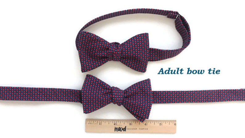 May include: Two bow ties with a red and blue patterned design. The larger bow tie is labeled "Adult bow tie". A ruler is below the bow ties.