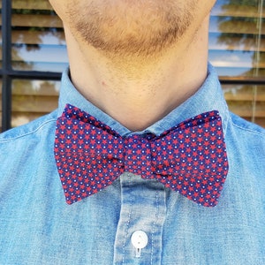May include: A blue denim shirt with a red and white bow tie featuring a star pattern.
