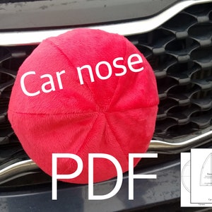 May include: A red plush car nose cushion with the text "Car nose" and "PDF" printed on it. The cushion is sitting on the front grille of a car.