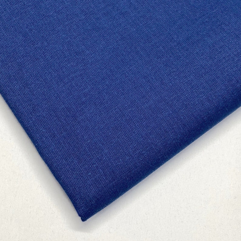 May include: A close-up of a piece of dark blue fabric. The fabric has a textured surface and a slightly rough feel.