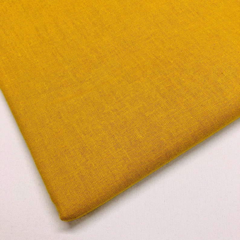 May include: A close-up of a piece of solid yellow fabric with a textured weave.