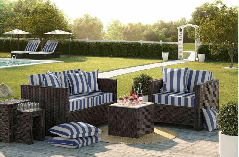 Puede incluir: Un conjunto de muebles de jard&iacute;n de mimbre marr&oacute;n con cojines a rayas azules y blancas. El conjunto incluye un sof&aacute; de dos plazas, dos sillones, una mesa de caf&eacute; y cojines. Los muebles est&aacute;n dispuestos en una terraza de madera en un jard&iacute;n.