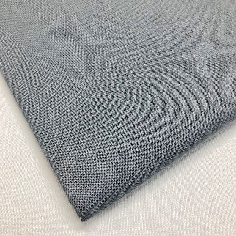 May include: A close-up of a piece of gray fabric with a subtle texture. The fabric is folded over on itself, showing the underside.