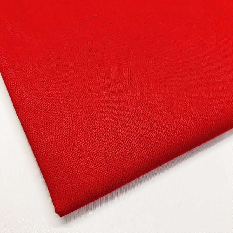 May include: A solid red fabric swatch. The fabric has a smooth, even texture.