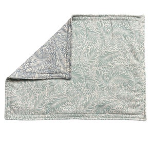 May include: A green and white floral patterned placemat with a folded edge.