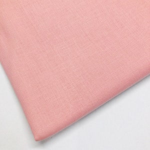 May include: A close-up of a soft, pale pink fabric. The fabric has a smooth, even texture.