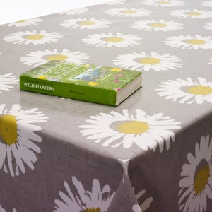 May include: A gray tablecloth with a white daisy pattern. A book titled "Collins Photoguide to Wild Flowers" is on top of the tablecloth.