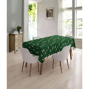May include: A green tablecloth with a Christmas tree and nutcracker pattern. The tablecloth is on a wooden table with two white chairs.
