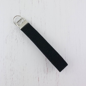 May include: A black canvas key chain with a silver key ring.