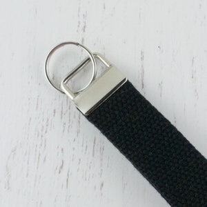 May include: A black canvas keychain with a silver key ring and a silver loop.