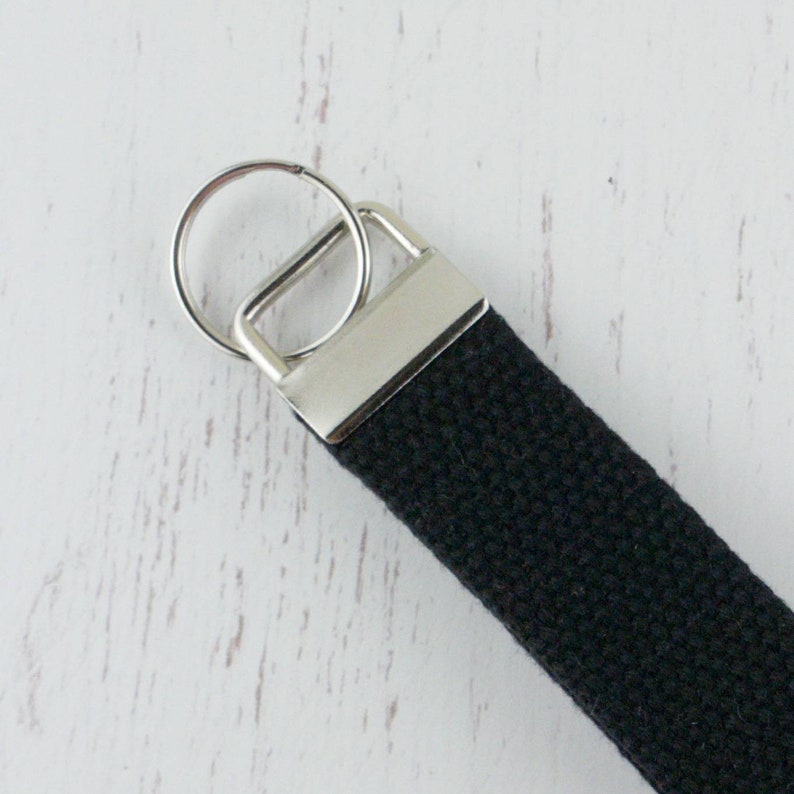 May include: A black canvas keychain with a silver key ring and a silver loop.