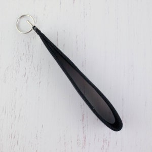 May include: A black fabric key chain with a silver metal key ring.