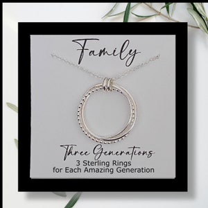 May include: Silver necklace with three intertwined rings, representing three generations. The necklace is displayed on a white card with the text "Family Three Generations 3 Sterling Rings for Each Amazing Generation".
