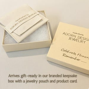 May include: A cream-colored gift box with the text "Handcrafted by ADORN DESIGNS JEWELRY" and "Celebrate, Honor, Remember..." printed on it. Inside the box is a jewelry pouch. The text "Arrives gift-ready in our branded keepsake box with a jewelry pouch and product card."
