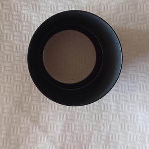 Puede incluir: Parasol de lente negro para un objetivo de c&aacute;mara. El parasol est&aacute; hecho de pl&aacute;stico y tiene una forma circular.