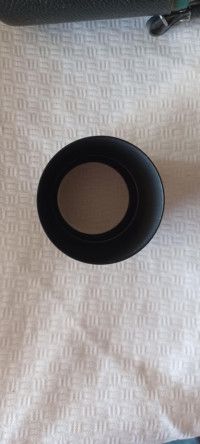 Puede incluir: Parasol de lente negro para un objetivo de c&aacute;mara. El parasol est&aacute; hecho de pl&aacute;stico y tiene una forma circular.