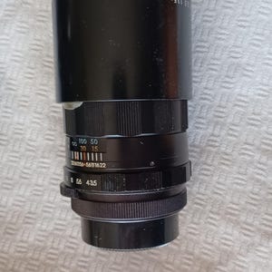 Puede incluir: Un objetivo de c&aacute;mara negro con un rango de zoom de 135 mm a 200 mm y una apertura m&aacute;xima de f/5.6. El objetivo tiene una escala de profundidad de campo y un anillo de enfoque.