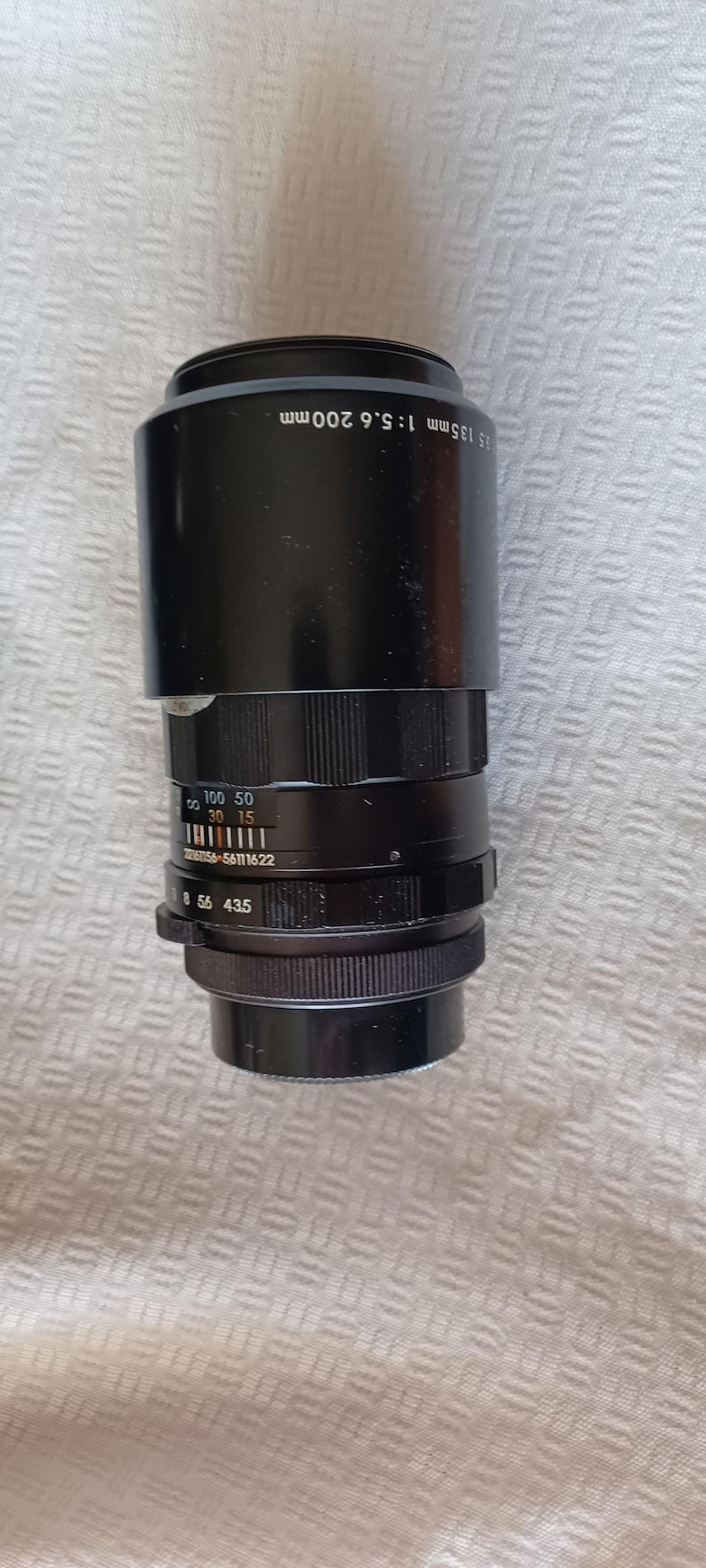 Puede incluir: Un objetivo de c&aacute;mara negro con un rango de zoom de 135 mm a 200 mm y una apertura m&aacute;xima de f/5.6. El objetivo tiene una escala de profundidad de campo y un anillo de enfoque.