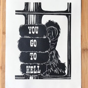 May include: Black and white linocut print of a monster with the words "YOU GO TO HELL" printed on its body.