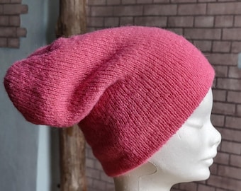 May include: A pink knitted beanie hat with a slouchy fit. The hat is made of a soft, fuzzy material.