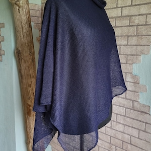Könnte beinhalten: Ein marineblauer Strickponcho mit lockerer, fließender Passform. Der Poncho ist aus einem leichten, atmungsaktiven Stoff gefertigt und hat ein schlichtes, elegantes Design.