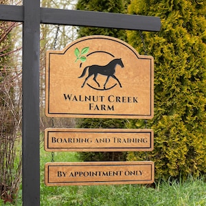 May include: A wooden sign for Walnut Creek Farm, featuring a black horse silhouette and the text "Boarding and Training" and "By Appointment Only." The sign is mounted on a black post with a natural background.