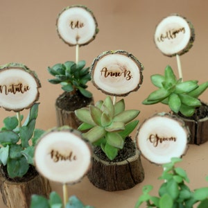 Wedding table decors- place cards and a gift for guests. Naturally dried oak pots for succulents with laser engraved wooden name tags. Set of 6 in this picture on a brown background