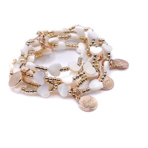 May include: A multi-strand bracelet with gold beads and white heart-shaped beads. The bracelet has several charms with the word "Forever" inscribed on them.