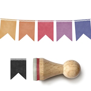 Puede incluir: Un sello de madera con un diseño de banderín y una hilera de banderines de colores. El sello tiene un mango redondo de madera y una forma de banderín negro. Los banderines son de varios colores, incluyendo amarillo, naranja, rosa, morado, azul y turquesa.