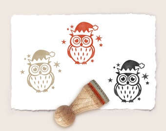 Puede incluir: Tres sellos de goma que representan un búho de dibujos animados con un gorro de Papá Noel. El búho está rodeado de estrellas. Los sellos están sobre un fondo blanco.