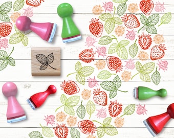 May include: A set of five wooden stamps with different designs, including a leaf, a strawberry, and a heart. The stamps are on a white wooden background.