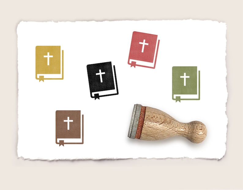 May include: Five rubber stamps with a book and cross design in different colors: gold, black, red, brown, and green. The stamps are on a white paper background. A wooden stamp handle is also shown.