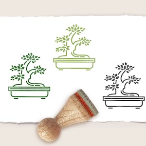 Könnte beinhalten: Drei Stempel aus Gummi mit einer Linienzeichnung eines Bonsai-Baums in einem Topf. Die Stempel befinden sich auf einem weißen Papierhintergrund. Der obere Stempel ist grün, der mittlere Stempel ist grün und der untere Stempel ist schwarz.