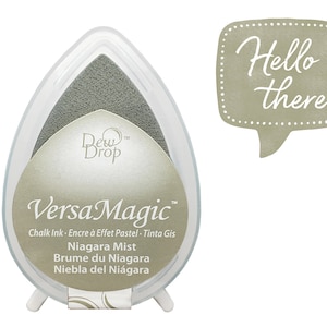 May include: A gray ink pad with the text "Dew Drop" and "VersaMagic Chalk Ink. Encre à Effet Pastel - Tinta Gis" and the text "Niagara Mist Brume du Niagara Niebla del Niágara". The ink pad is in the shape of a teardrop and has a white base.