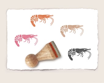 May include: A wooden rubber stamp with a red handle and a design of a shrimp in black, pink, and orange.